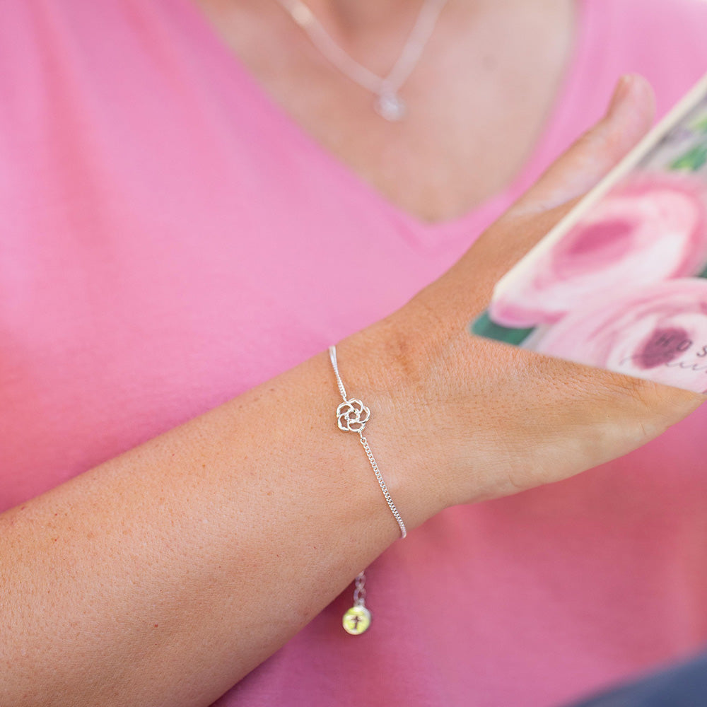 A woman wearing our almond blossom logo Christian bracelet in sterling silver holding a Bible is a reminder that God is always watching over you.