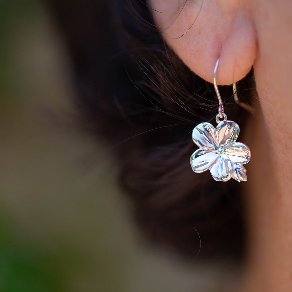Inspired by the symbolism of the Almond Blossom, these earrings serve as a reminder that God is constantly watching over you. Christian earrings in sterling silver hook style in the ear of a dark haired woman  From our Mary Magdalene Collection