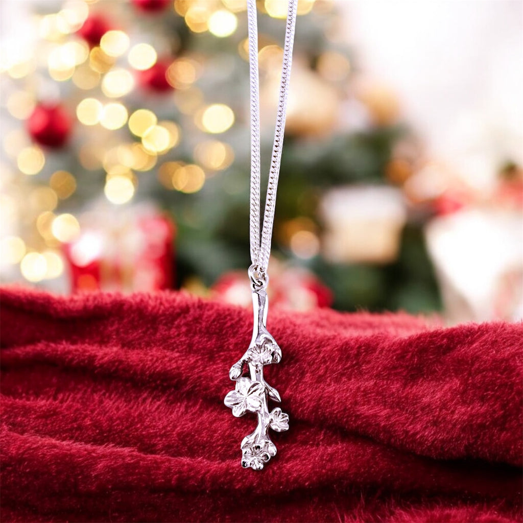 Silver necklace with a floral pendant on a red fabric background with a blurred festive background.