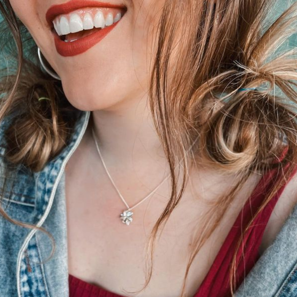 Young woman wearing our Mary Magdalene Christian necklace of an almond blossom and bud in sterling silver inspired by the Word of God as a reminder of His watchfulness over you life..