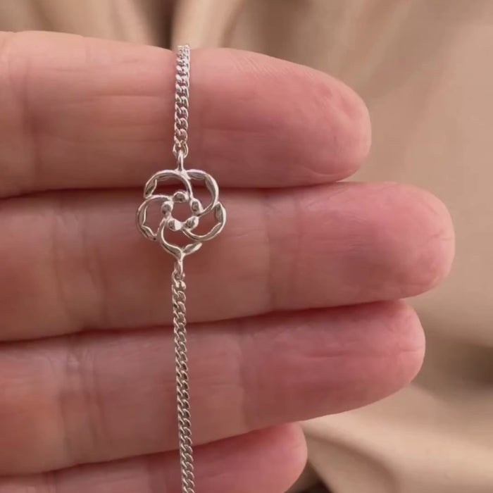 A woman holding a sterling silver bracelet showing the details and symbolism of the almond blossom in the Word of God. He is Watching over you.