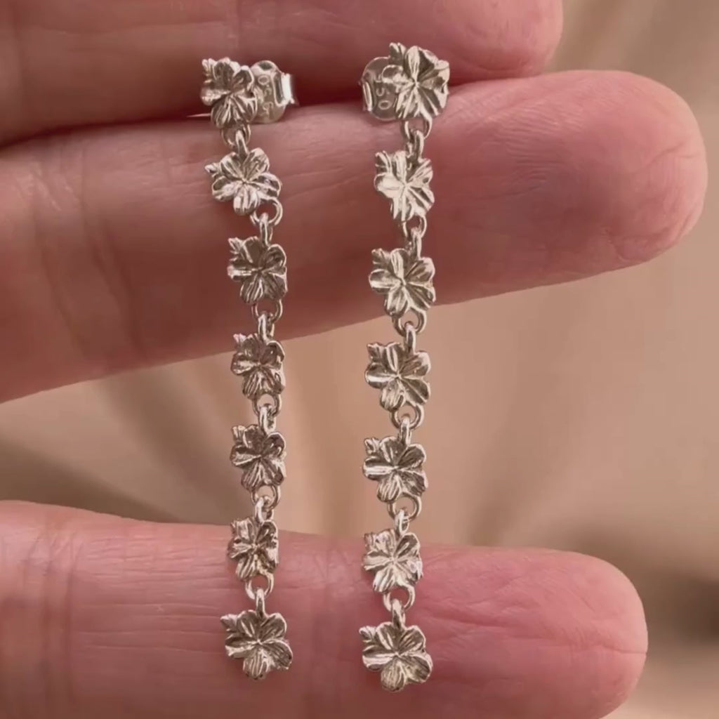 Sterling silver Christian earrings of a floral almond blossoms design on  woman's hand showcasing details 