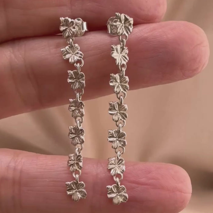 Sterling silver Christian earrings of a floral almond blossoms design on  woman's hand showcasing details 