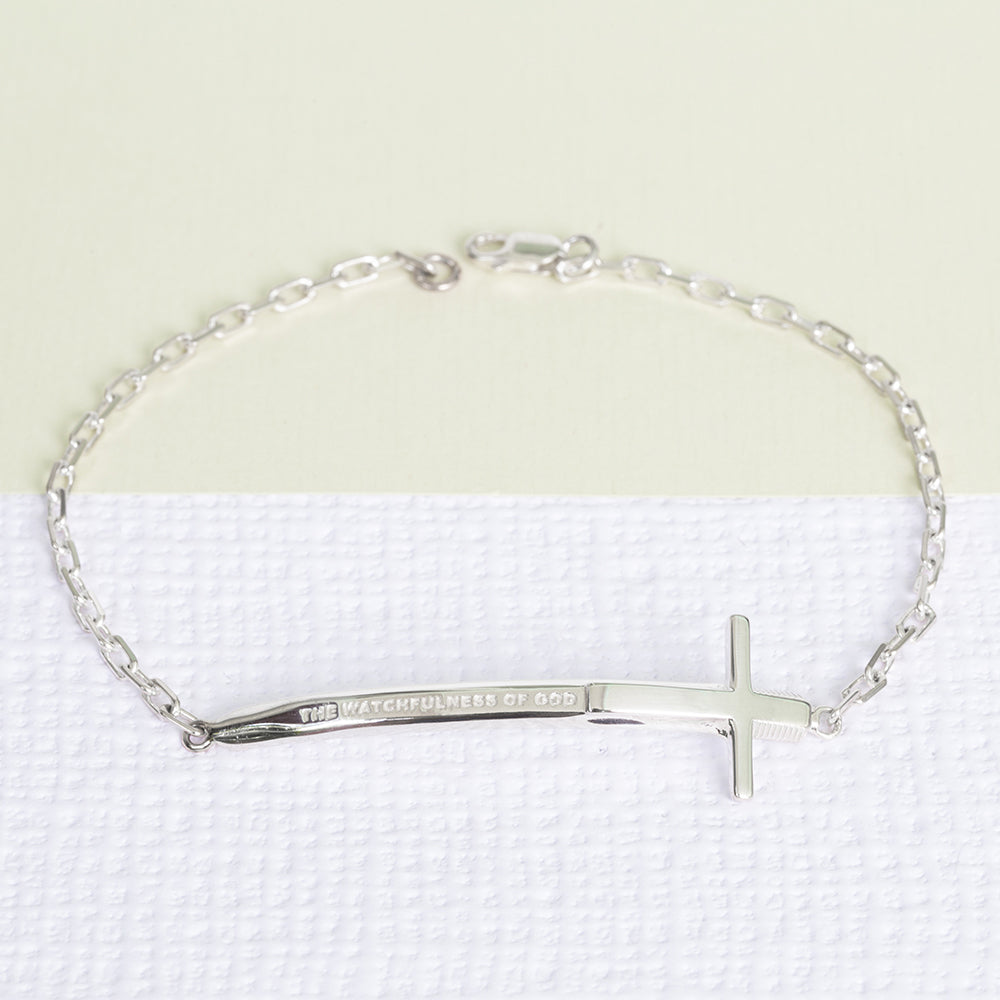 Christian bracelet in sterling silver in the format of a sword and a cross with "The Watchfulness of God" written on it. The bracelet is on a piece write textured paper and a green one