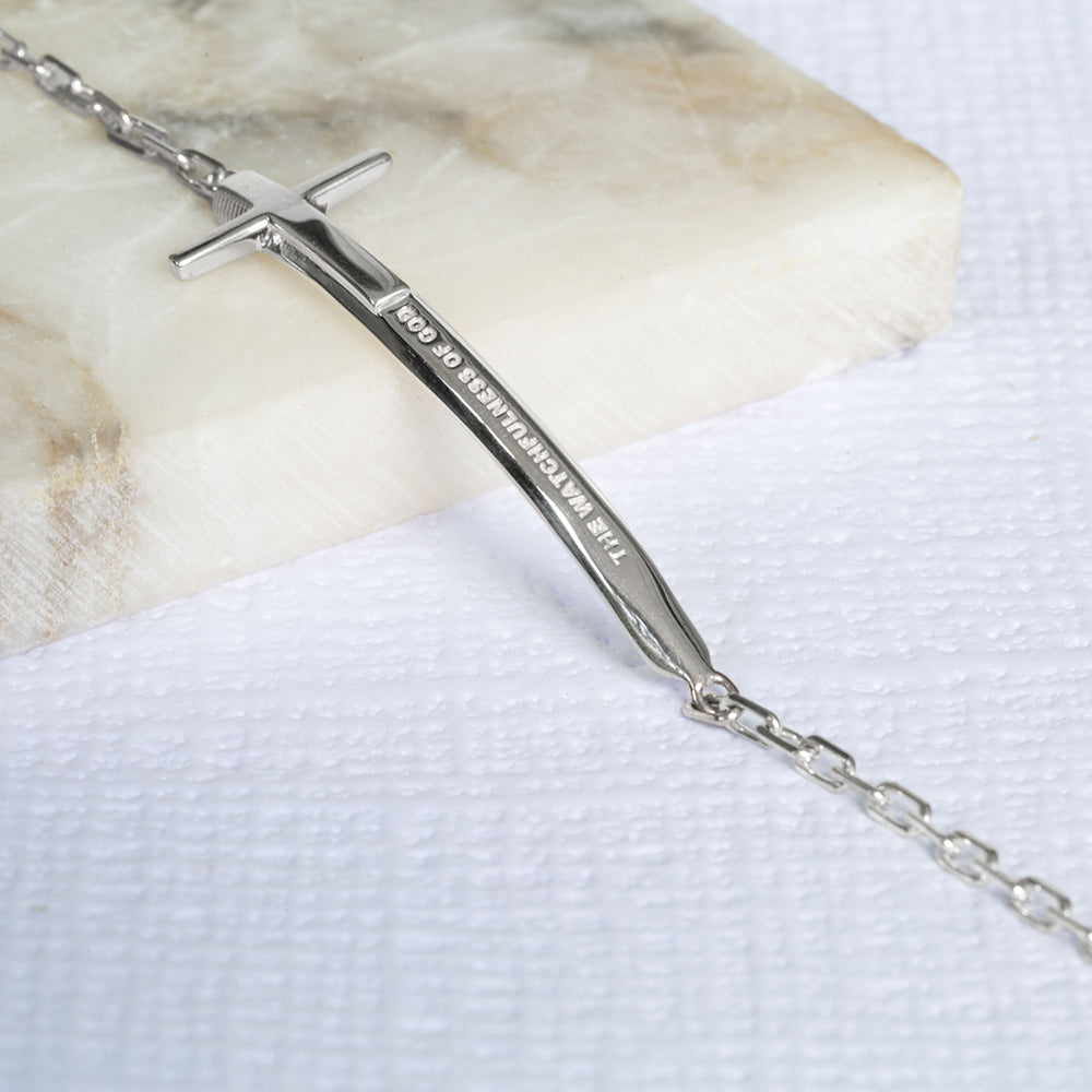 Christian bracelet in sterling silver in the format of a sword and a cross with "The Watchfulness of God" written on it. The bracelet is on a piece of marble and a write textured paper