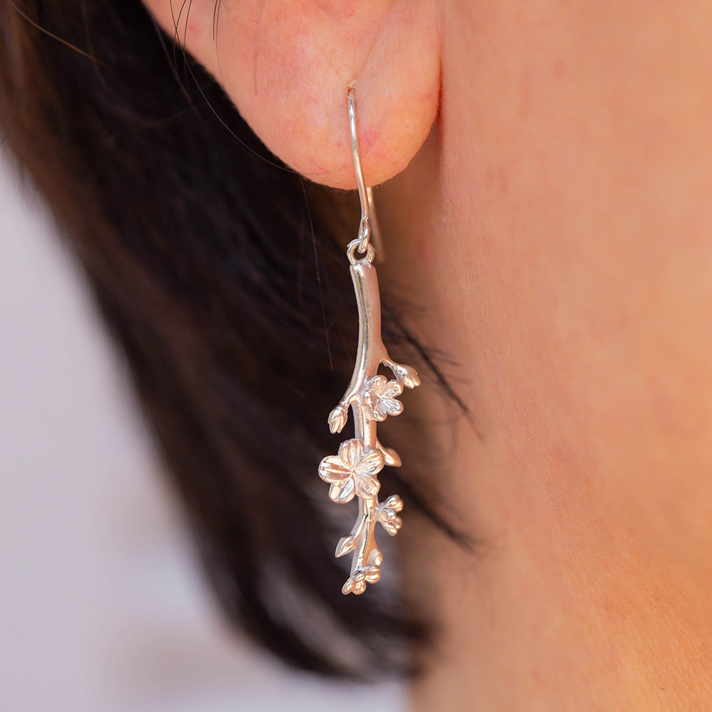 Our Esther Christian Earrings, the branch of an almond tree in sterling silver hook style pictured on an ear of a woman with short dark hair