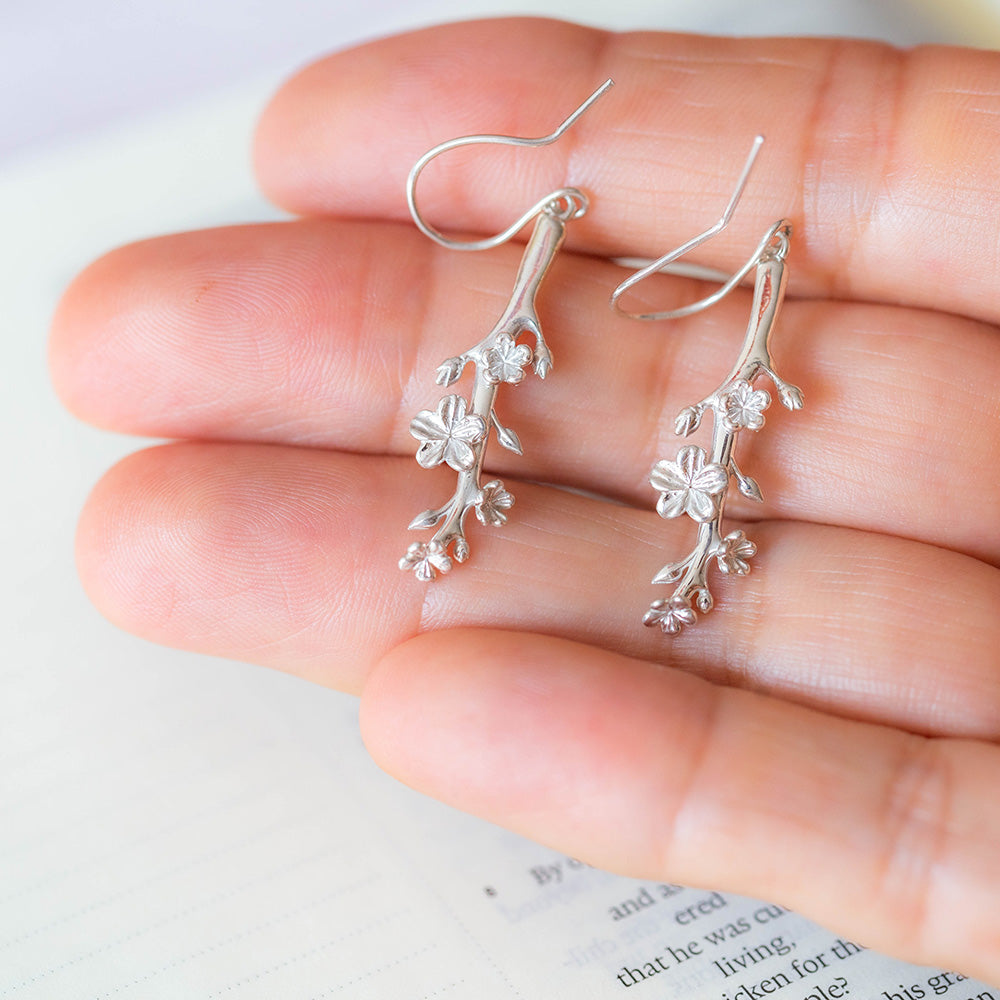 Our Esther Christian Earrings, the branch of an almond tree in sterling silver hook style on the hand of a woman with a Bible in  the background
