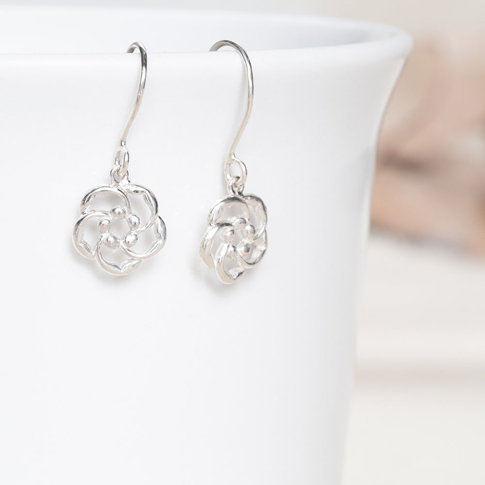  Our almond blossom logo Christian earrings in sterling silver, hook style on a white coffee cup, are a reminder of God's loving watchfulness over your life