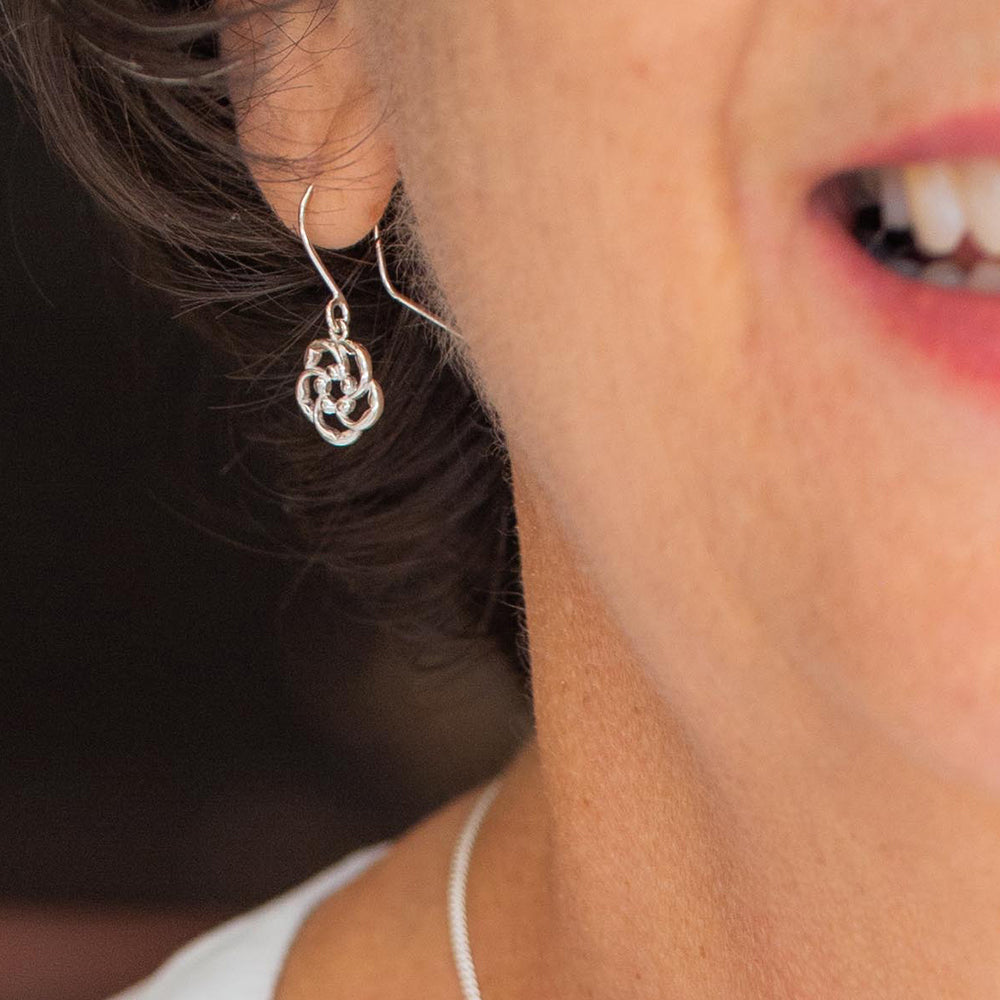 A woman wearing our almond blossom logo Christian hook style earrings in sterling silver,  are a reminder of God's loving watchfulness over your life.