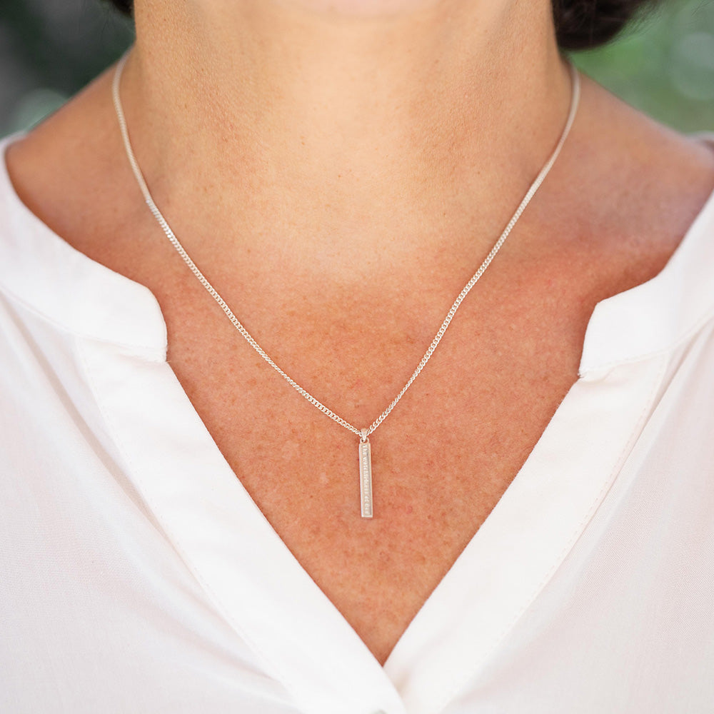 The Watchfulness of God engraved on a sterling silver bar necklace  serves as a reminder of God's watchful and caring presence in your life. Christian necklace shown on a woman in a white blouse