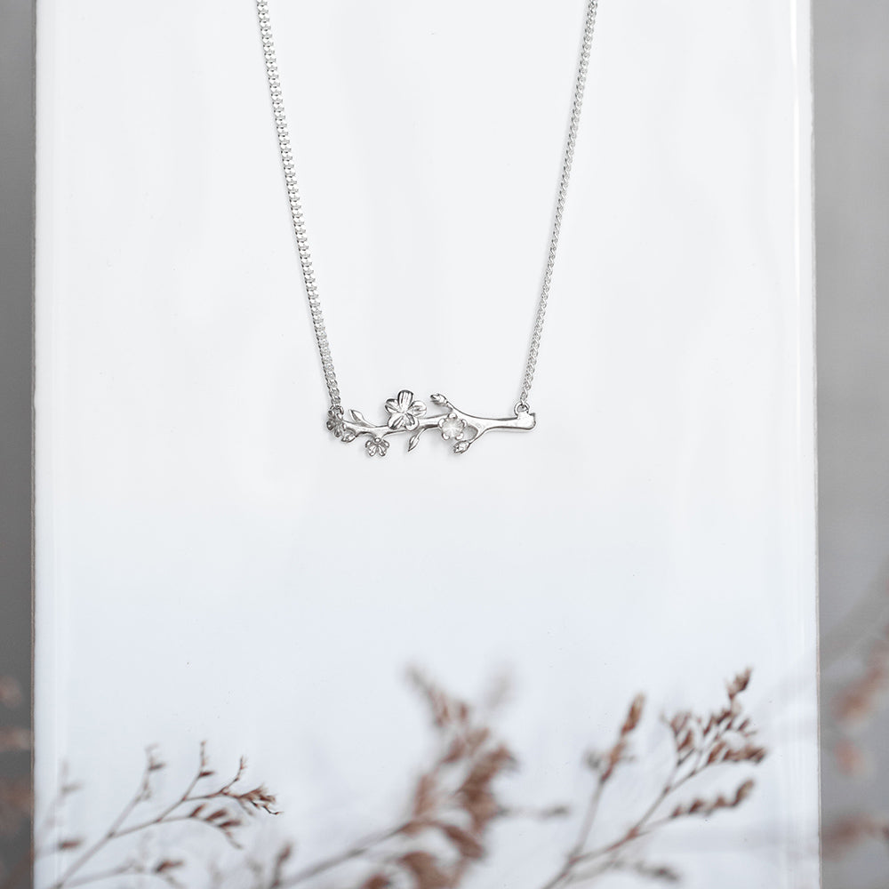 Our Esther Christian necklace, the branch of an almond tree in sterling silver on a white background with dried small flowers on the bottom