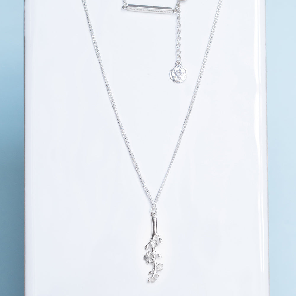 Our Esther Christian necklace the branch of an almond tree in sterling silver displaying our watchfulness of God bar extension with our logo and cross on a white tile and light blue background