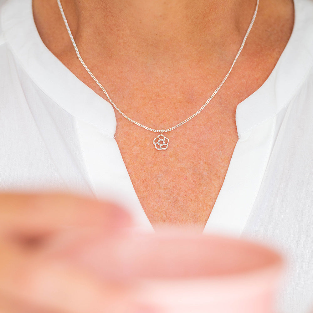 A woman wearing our almond blossom logo Christian necklace in sterling silver as a reminder that God is lovingly watching over you at all times