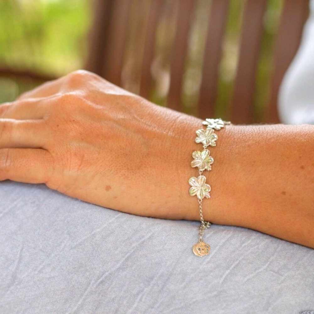 A Christian bracelet crafted from sterling silver, featuring seven stunning almond flower buds and blossoms,and there Biblical meaning serving as a symbol of God's loving watchfulness over our lives on a woman in a grey dress