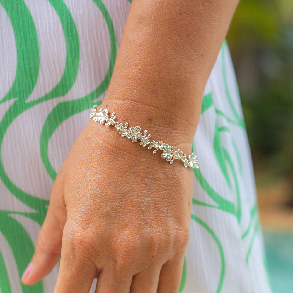 Woman wearing our Esther 22 large amond blossoms Christian bracelet in sterling silver wearing a white and green dress